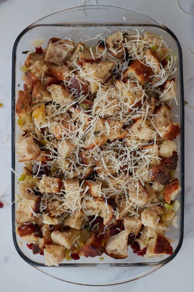 Parmesan cheese added on top of unbaked sourdough stuffing in a 9x13 pan.