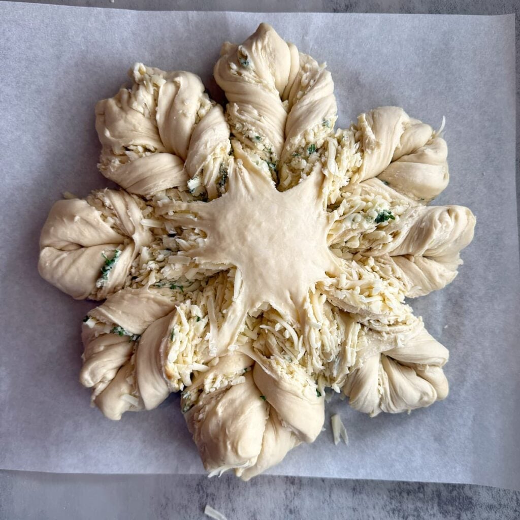 Cheesy Sourdough Star Bread shaped into a star on parchment paper.