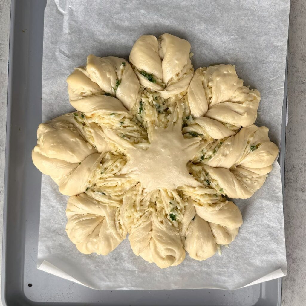 Cheesy Sourdough Star Bread after second rise on a parchment lined baking sheet.