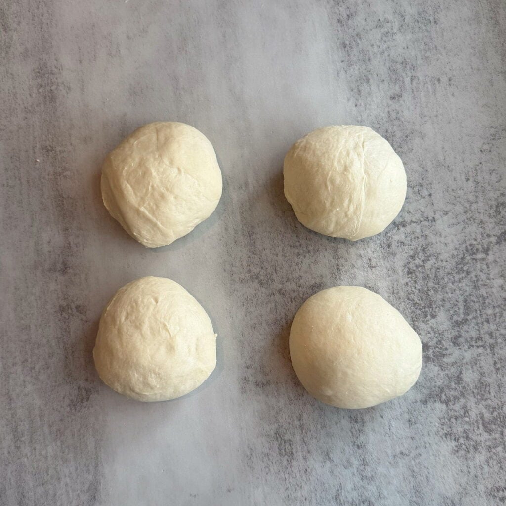 Four equal pieces of dough for Cheesy Sourdough Star Bread.