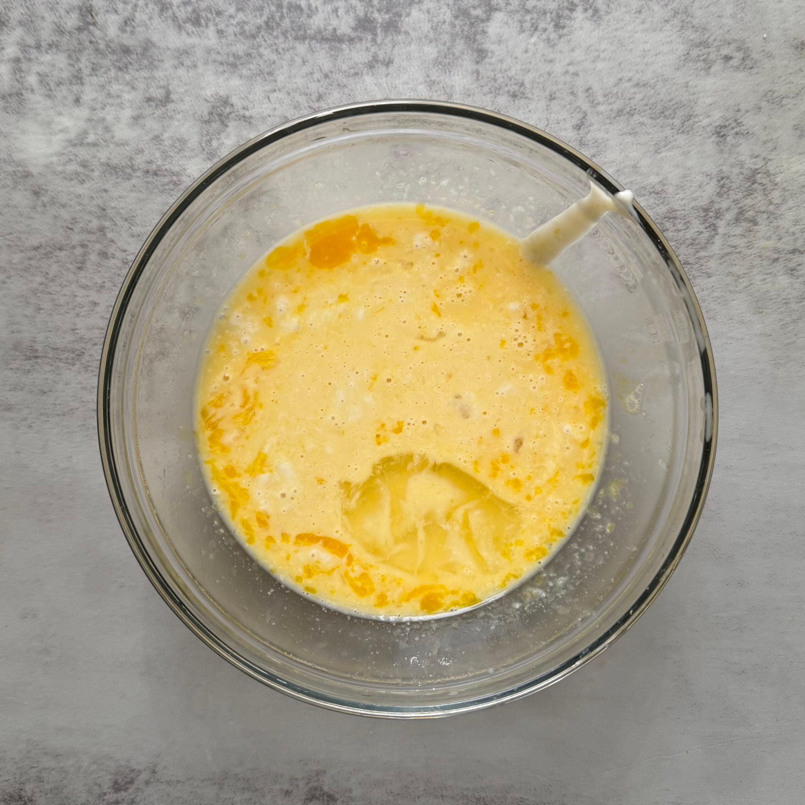 Wet ingredients mixed together in a glass bowl for cranberry orange sourdough scones.