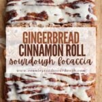 Sourdough gingerbread cinnamon roll focaccia with cream cheese icing on a wooden cutting board.