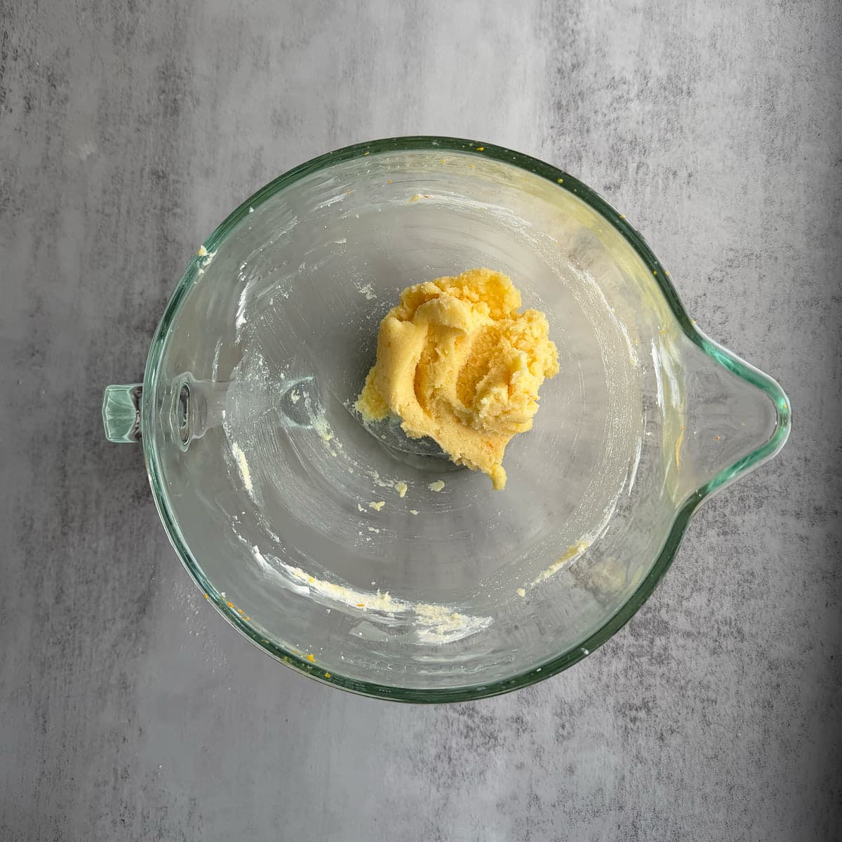 Butter and orange zest mixed with sugar in a glass bowl. 