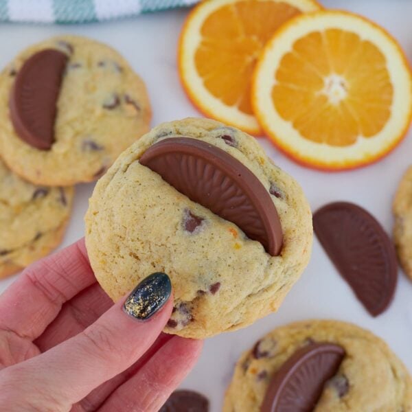 Hand holding a sourdough cookie with a chocolate orange on top.