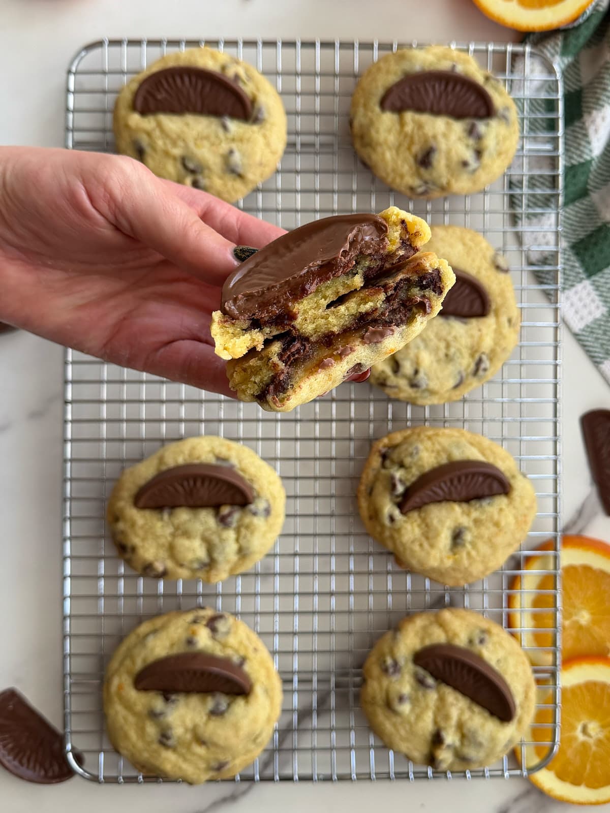 Hand holding a chocolate orange cookie split in half showing the middle of the cookie. 