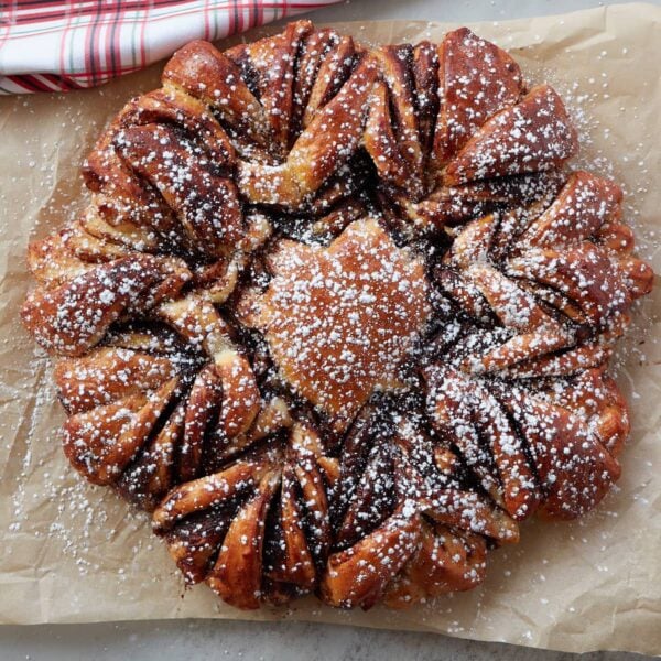 Sourdough discard nutella star bread on a piece of brown parchment paper next to a white and red cloth napkin.
