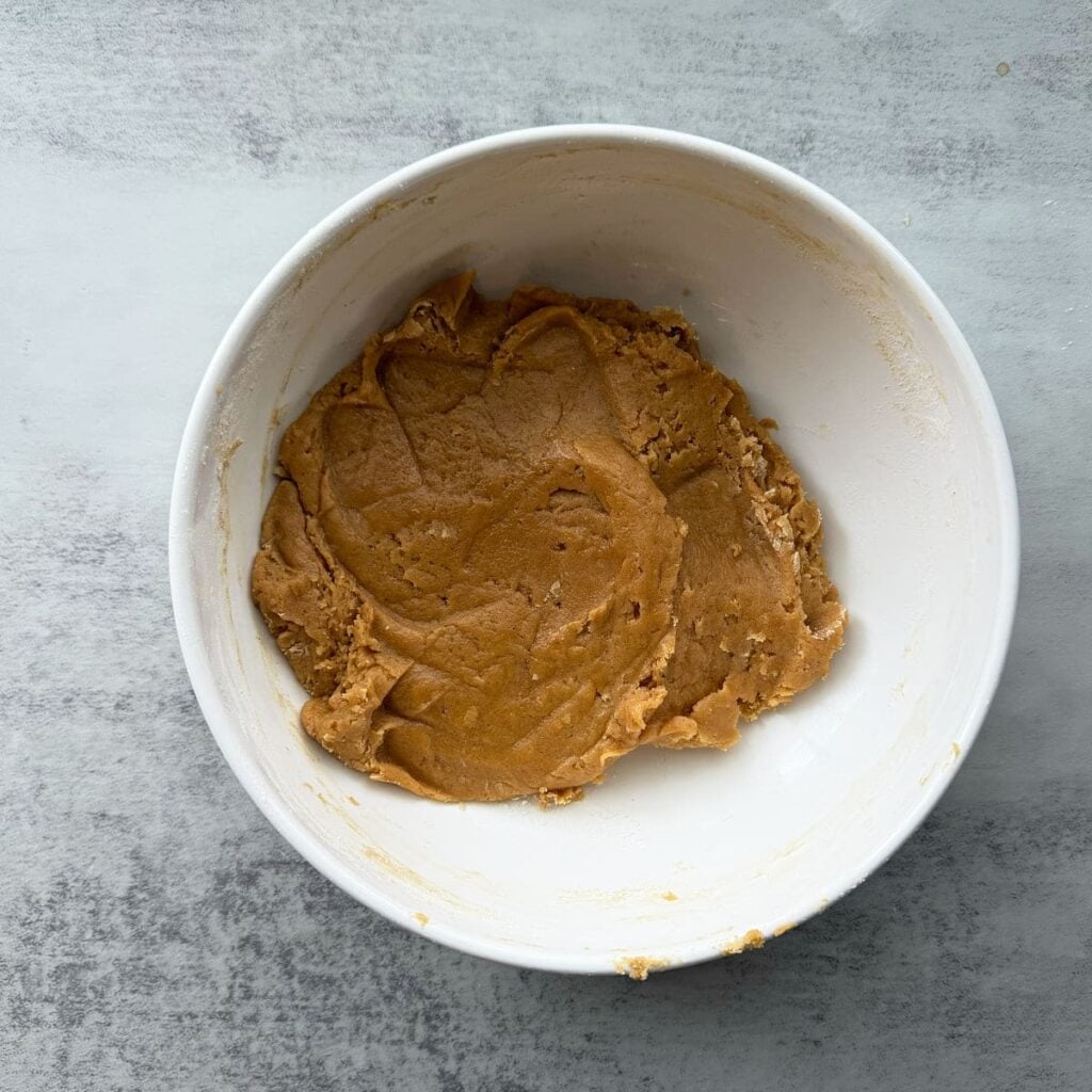 Dry ingredients added to the sourdough peanut butter cookie dough in a white bowl.