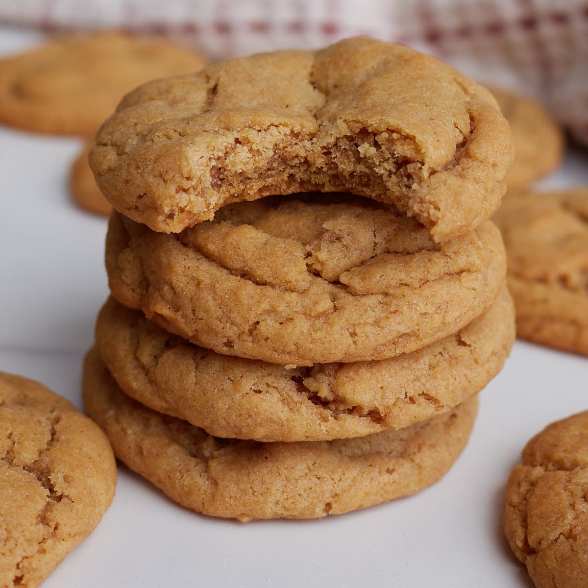 Four peanut butter sourdough cookies stacked on top of each other with a bite taken out of the top cookie.