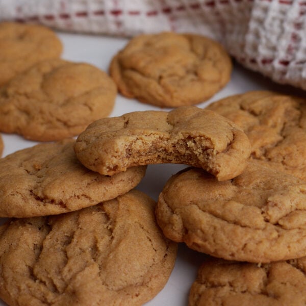 Sourdough Peanut Butter Cookies piled on top of each other with a bite taken out of the top cookie.
