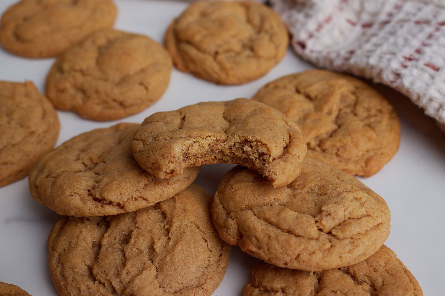 Sourdough Peanut Butter Cookies piled on top of each other with a bite taken out of the top cookie.