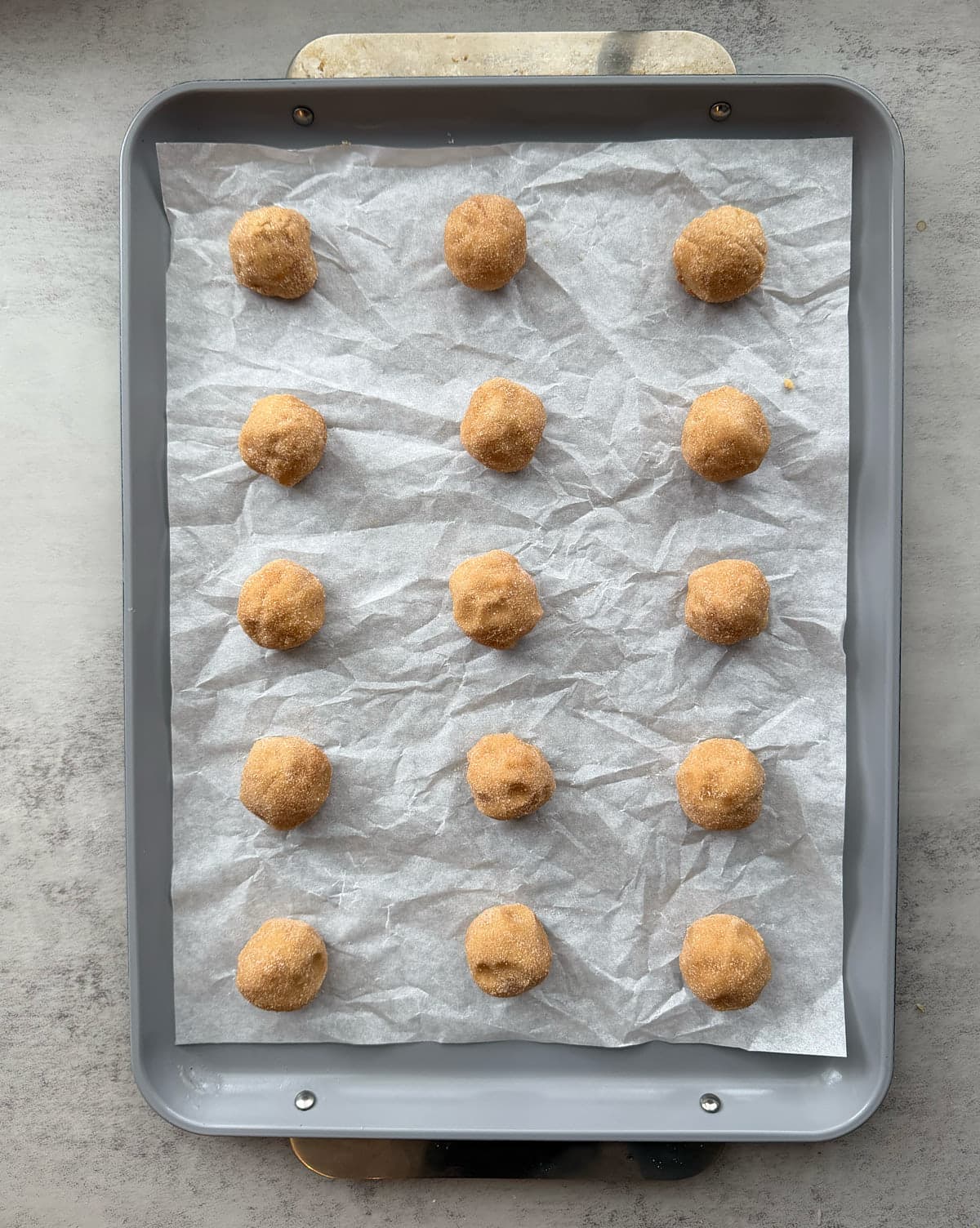 12 cookie dough balls on a parchment-lined cookie sheet.