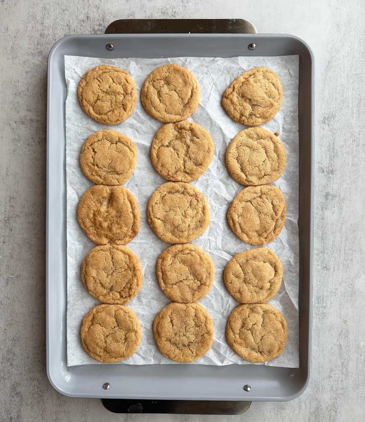 Freshly baked Sourdough Snickerdoodle Cookies on a parchment-lined baking sheet.