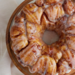 A Pinterest pin of a top-down photo of the monkey bread displayed on a wooden cake stand.