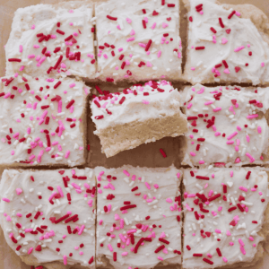 Sourdough sugar cookie bar with frosting and sprinkles cut into 9 bars. One bar is turned on its side.