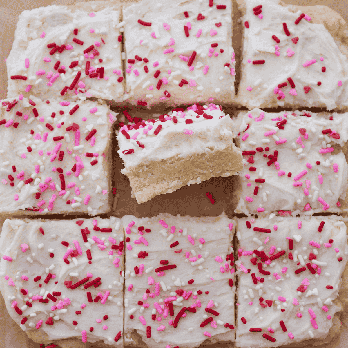 Sourdough sugar cookie bar with frosting and sprinkles cut into 9 bars. One bar is turned on its side.