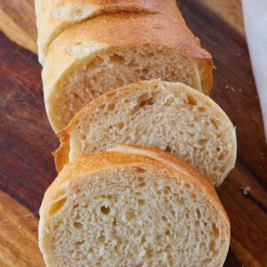 Sliced sourdough french bread on a wooden cutting board.