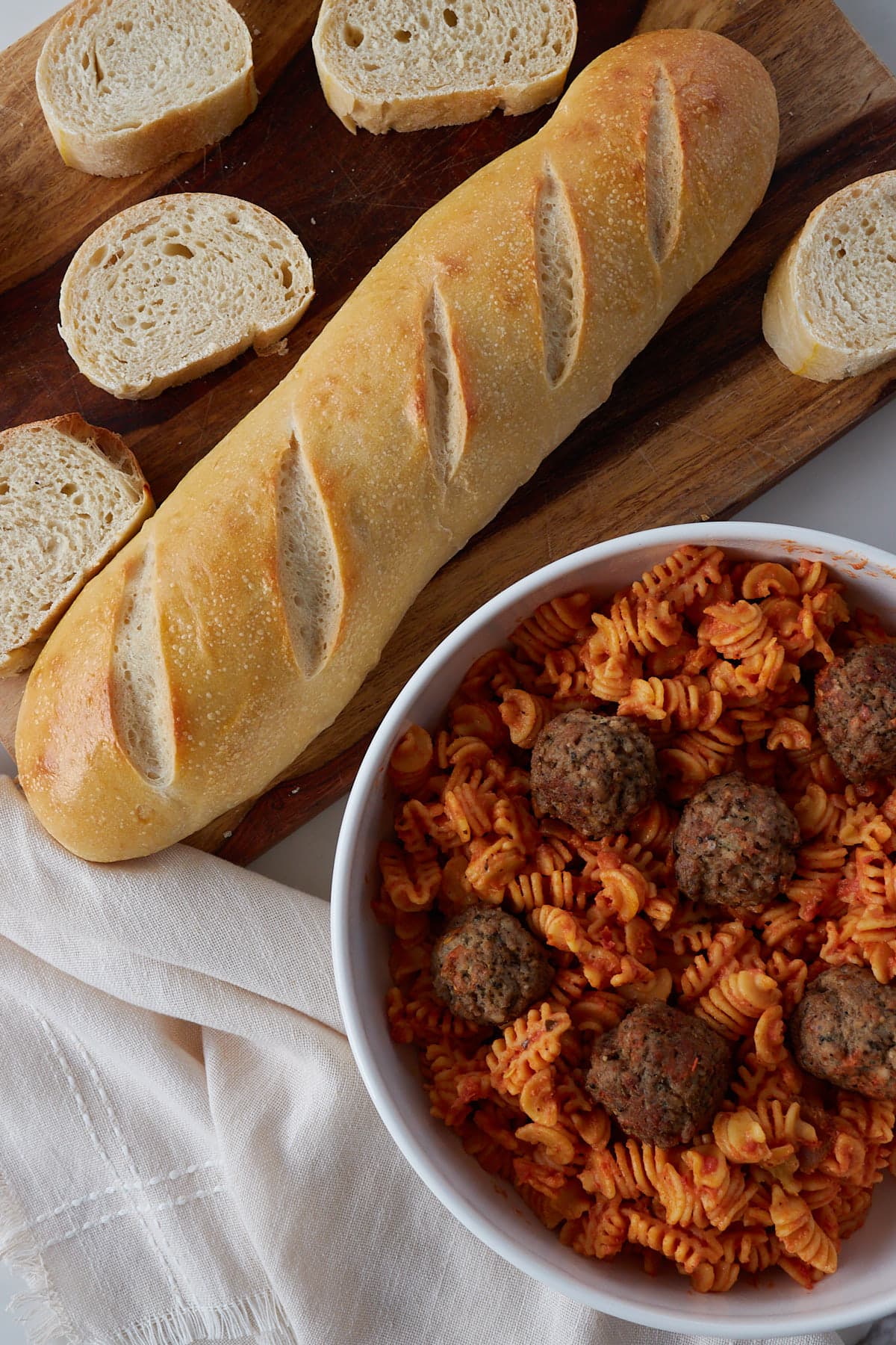 Sourdough french bread with a bowl of pasta and meatballs on the side.