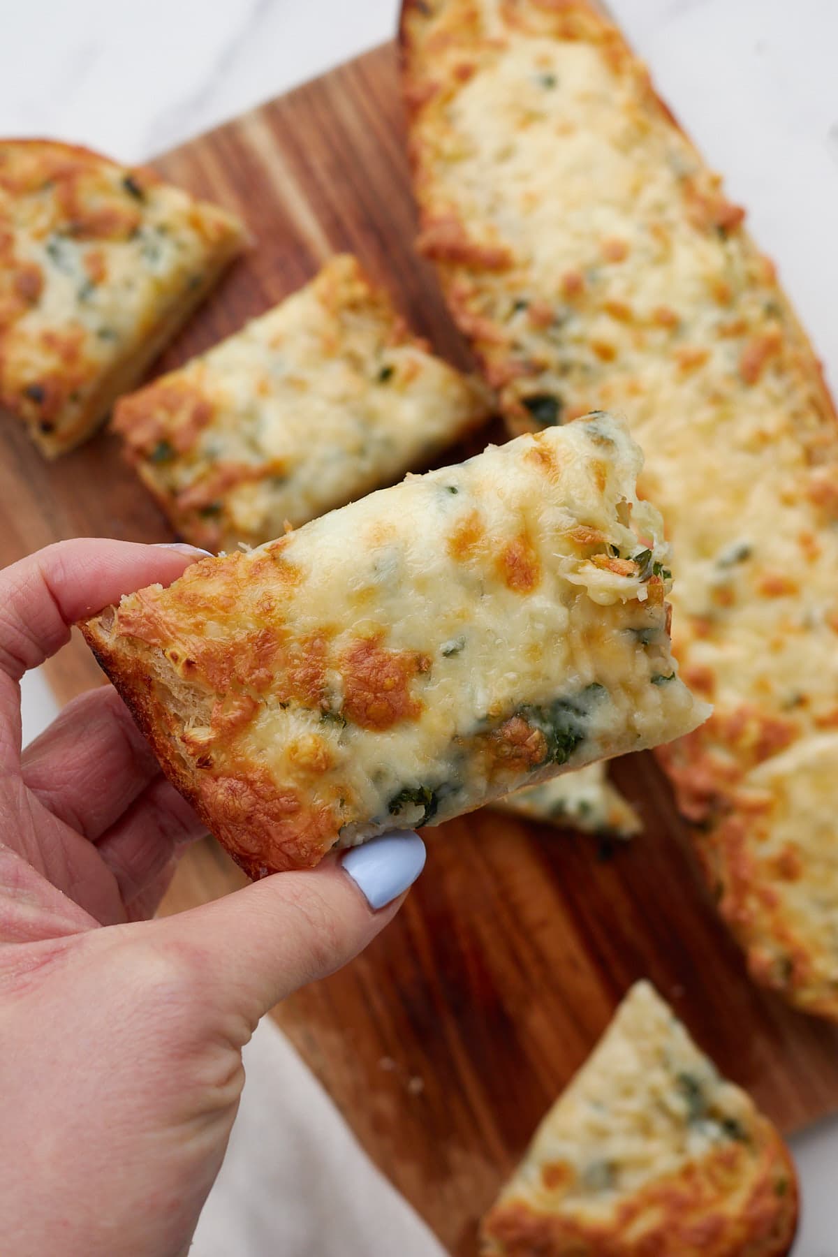 hand holding a slice of sourdough garlic bread