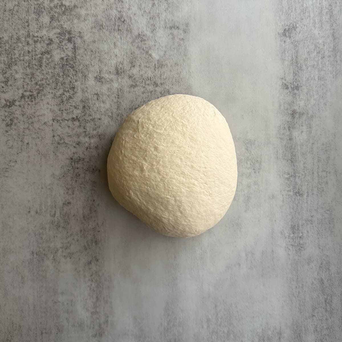 Ball of sourdough french bread dough on a gray counter. 