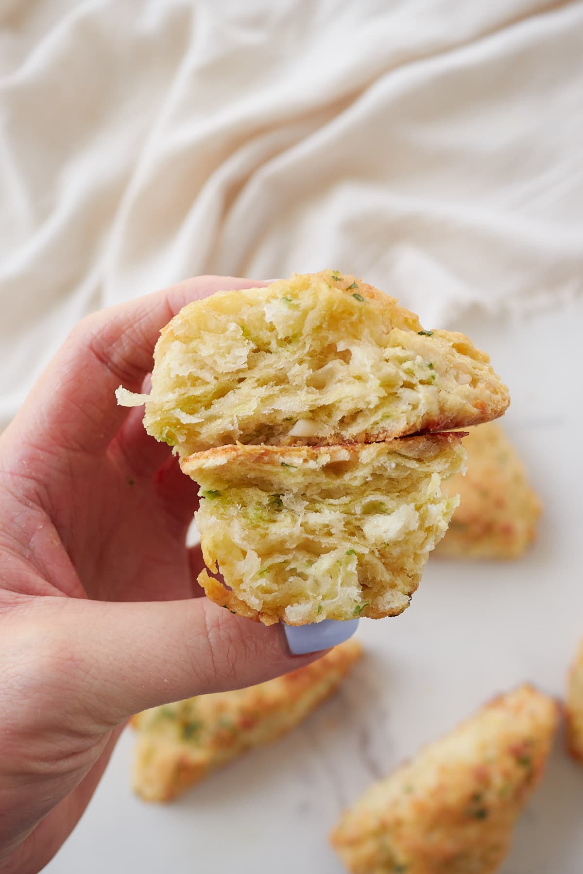 a hand holding a garlic scone torn in half to see the inside layers. 