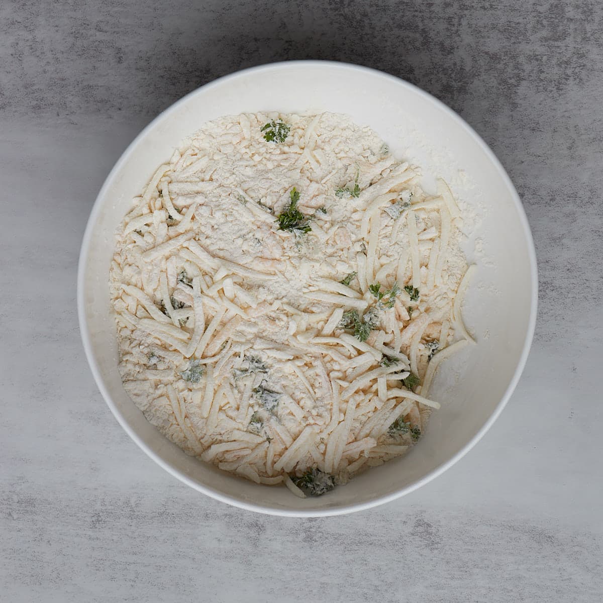 cheese and herbs added to dry ingredients in a bowl for scones.