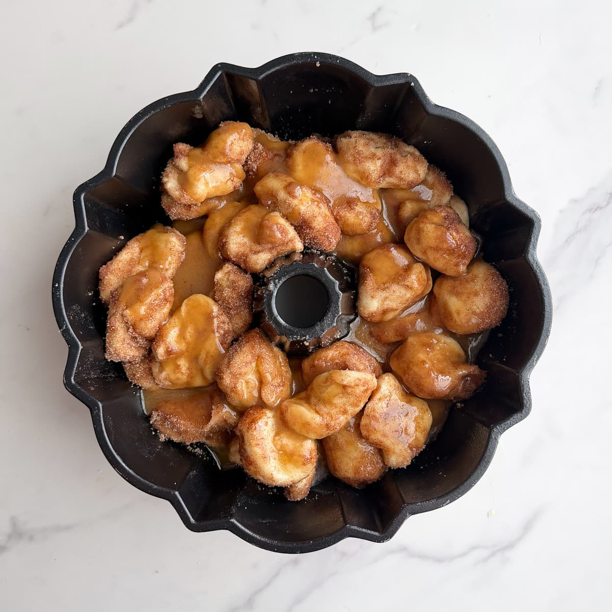 the first layer of sourdough monkey bread in a prepared bundt pan and coated with brown sugar coating.