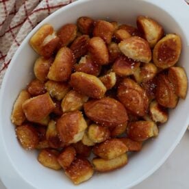 Close up of sourdough discard pretzel bites in a white bowl on a counter and a towel in the top left corner.
