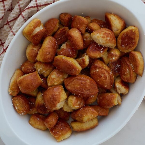 Close up of sourdough discard pretzel bites in a white bowl on a counter and a towel in the top left corner.