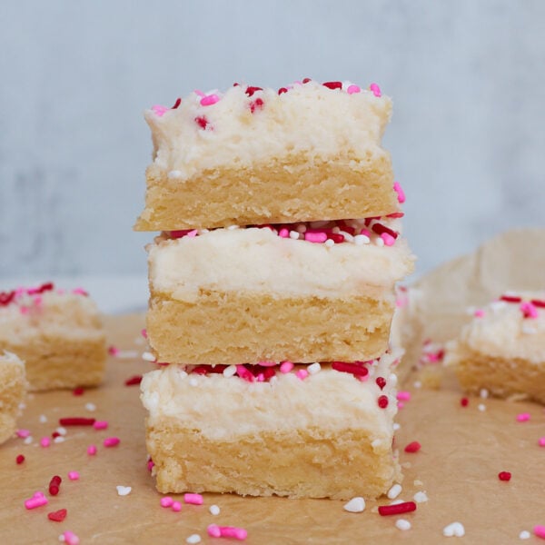 Stack of three sourdough sugar cookies on top of each other, each layered with frosting and sprinkles.