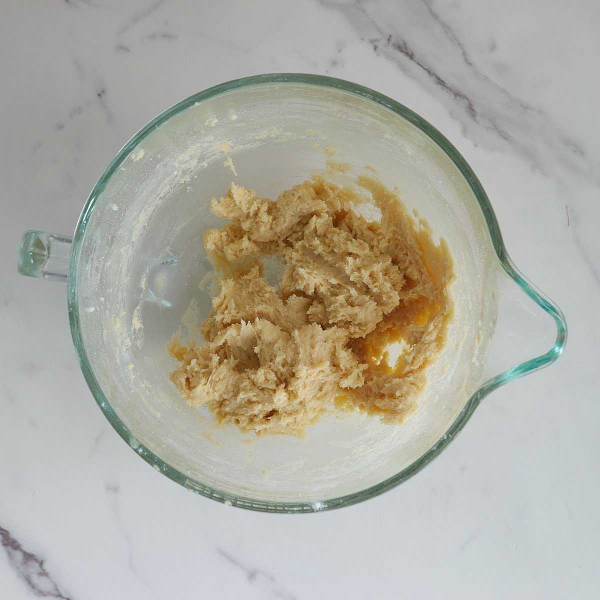 Remaining dry ingredients mixed with wet ingredients in a large glass mixing bowl.