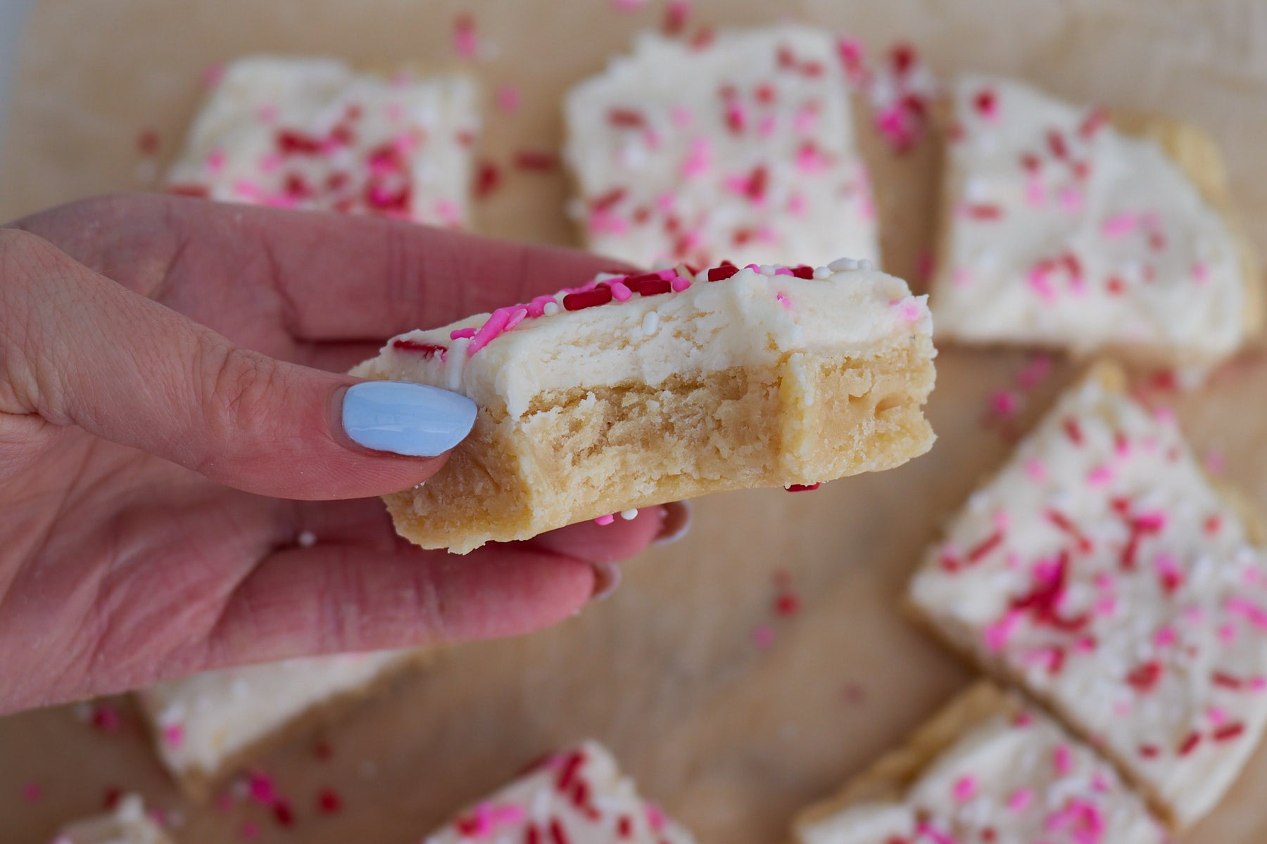 Hand holding a sourdough sugar cookie bar with a bite in it. 