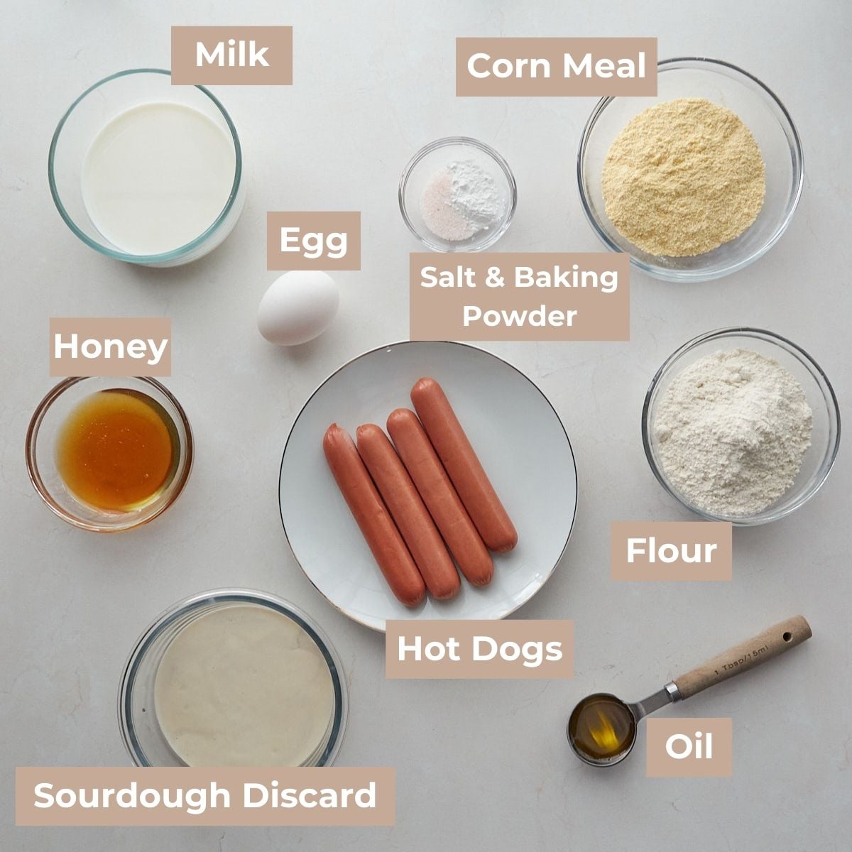 Ingredients for Sourdough Mini Corn Dogs in clear bowl on a white surface.