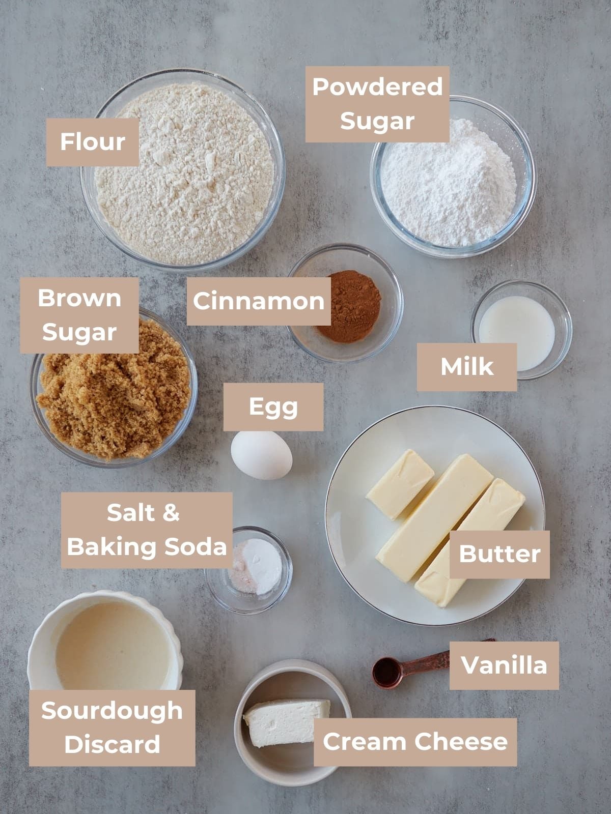 Ingredients for sourdough cinnamon roll cookies are arranged on a marble surface.