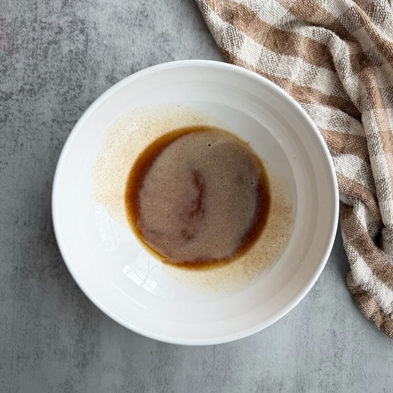 Browned butter in a white bowl. The bowl is on a marble counter with a kitchen towel beside it.