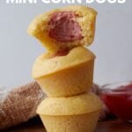 Three sourdough mini corn dogs stacked on top of each other with a bite taken out of the top sourdough mini corn dog.