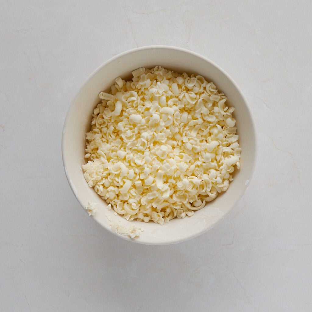 Frozen butter shredded in a white bowl.