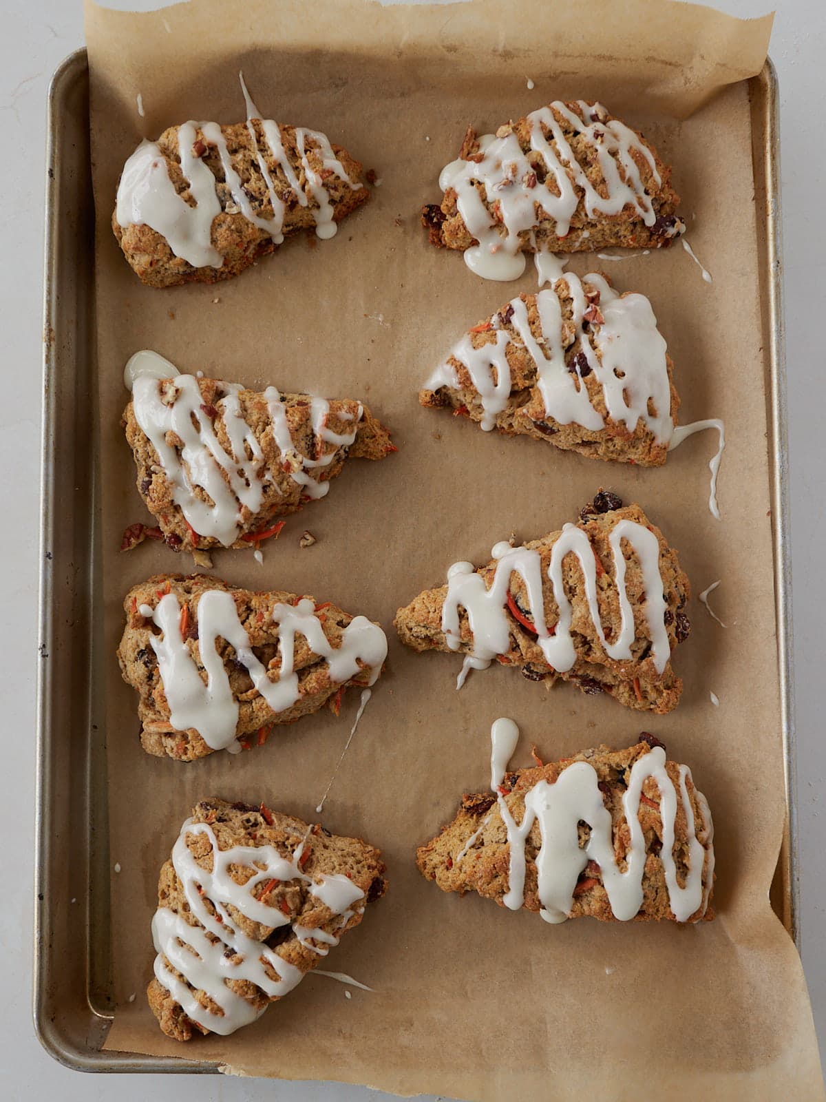 Cream Cheese frosting drizzled on top of Sourdough Carrot Cake Scones.