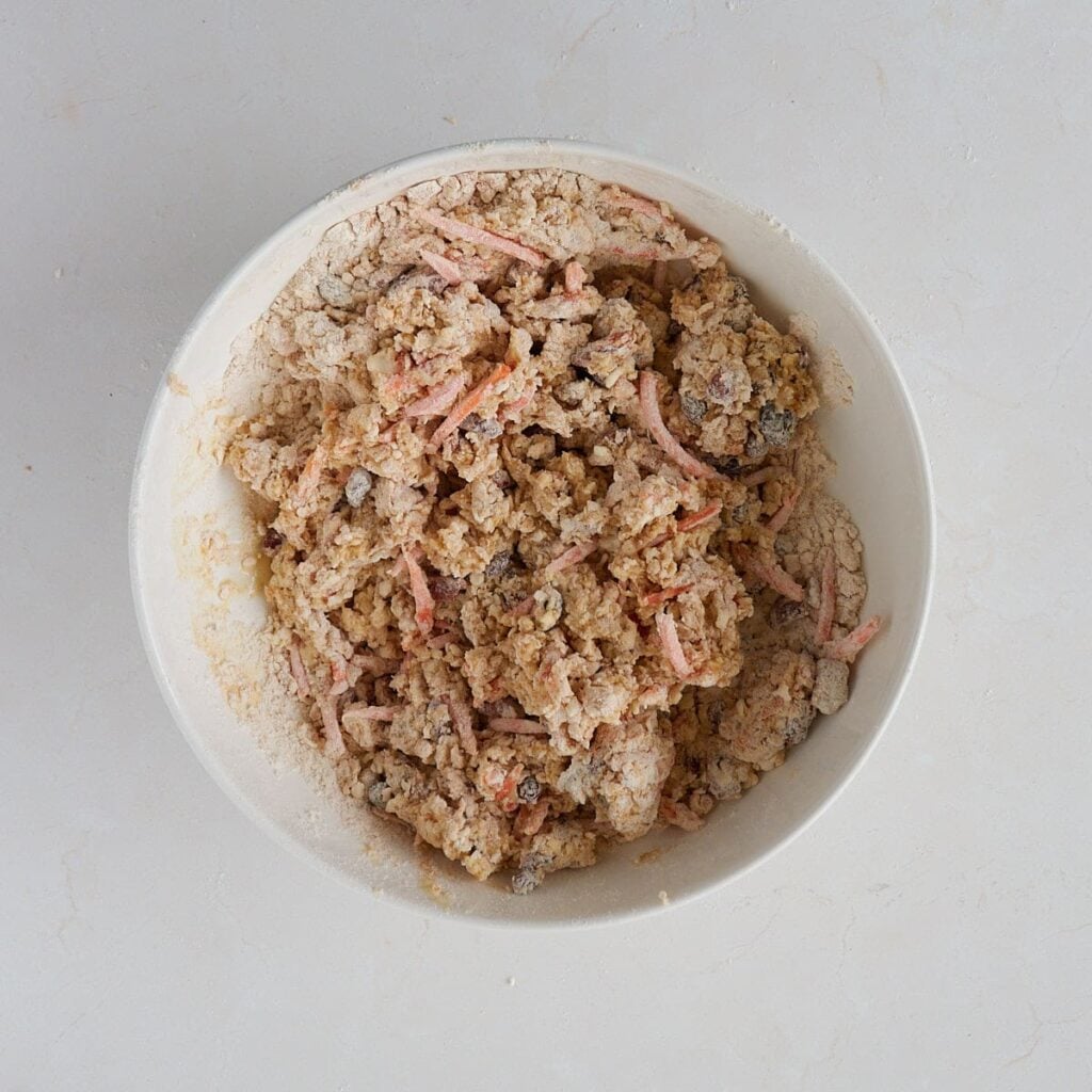 Wet ingredients added to the dry ingredients for Sourdough Carrot Cake Scones in white bowl.