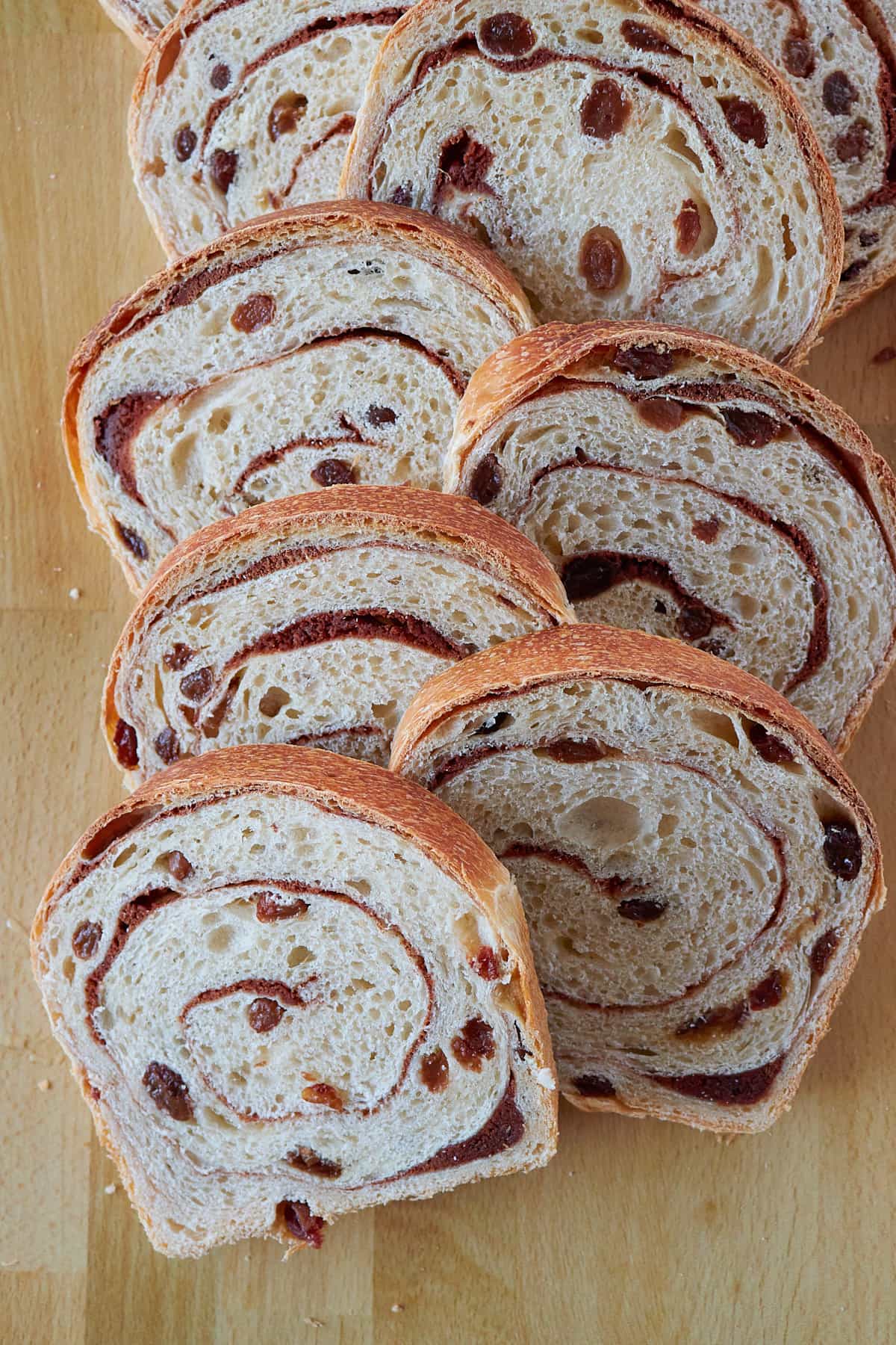 Slices of Sourdough Cinnamon Raisin Bread stacked together on a wooden surface.