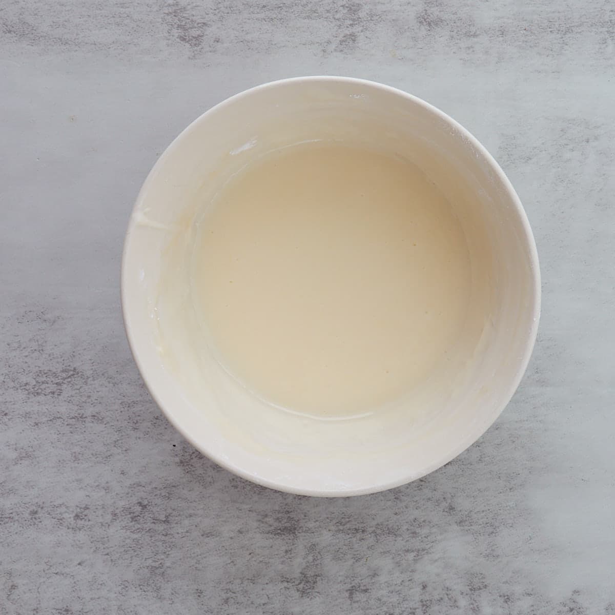Cream cheese icing mixed in a white bowl, ready to drizzle over the cookies.