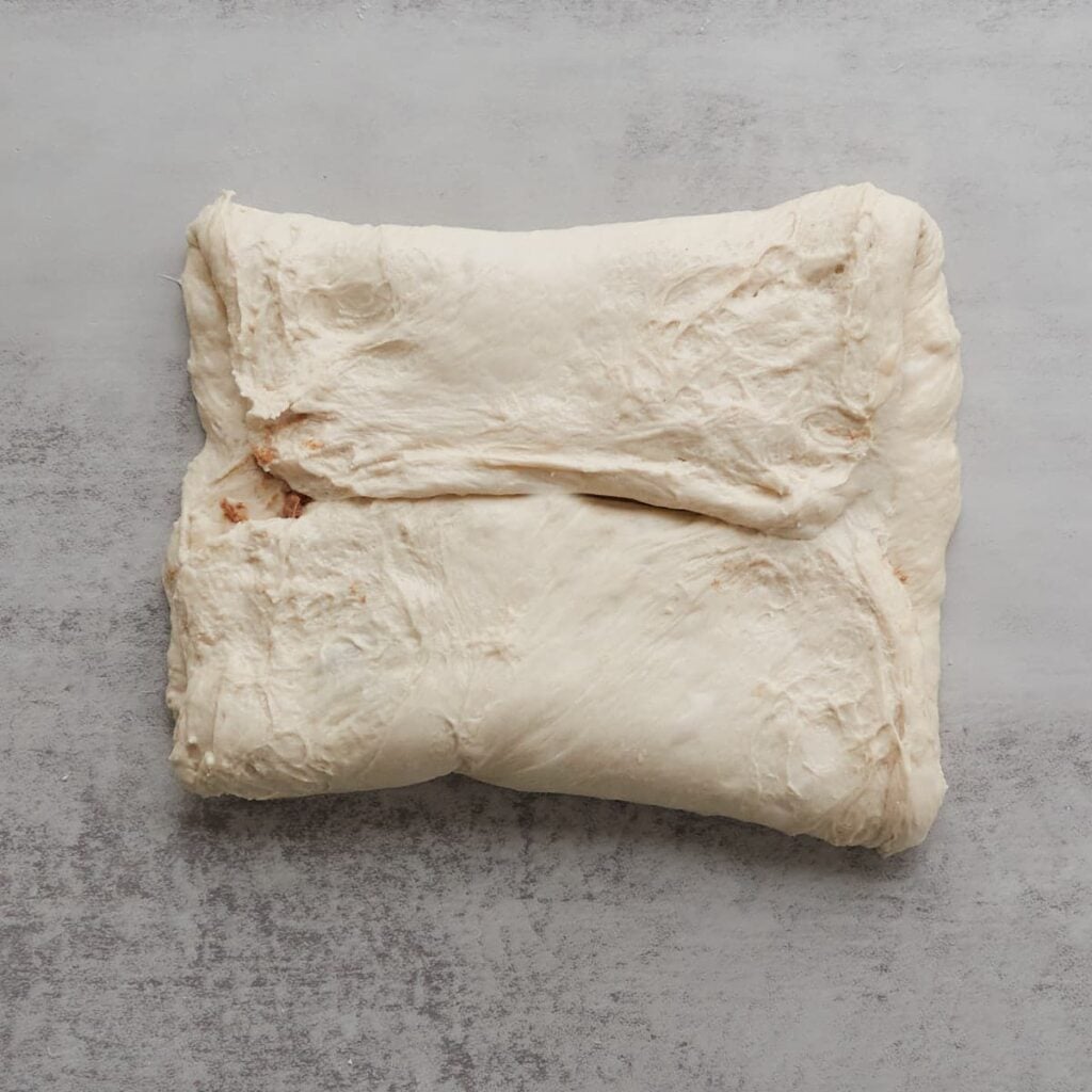 Bread dough folded on top of each other with cinnamon honey butter in the middle.