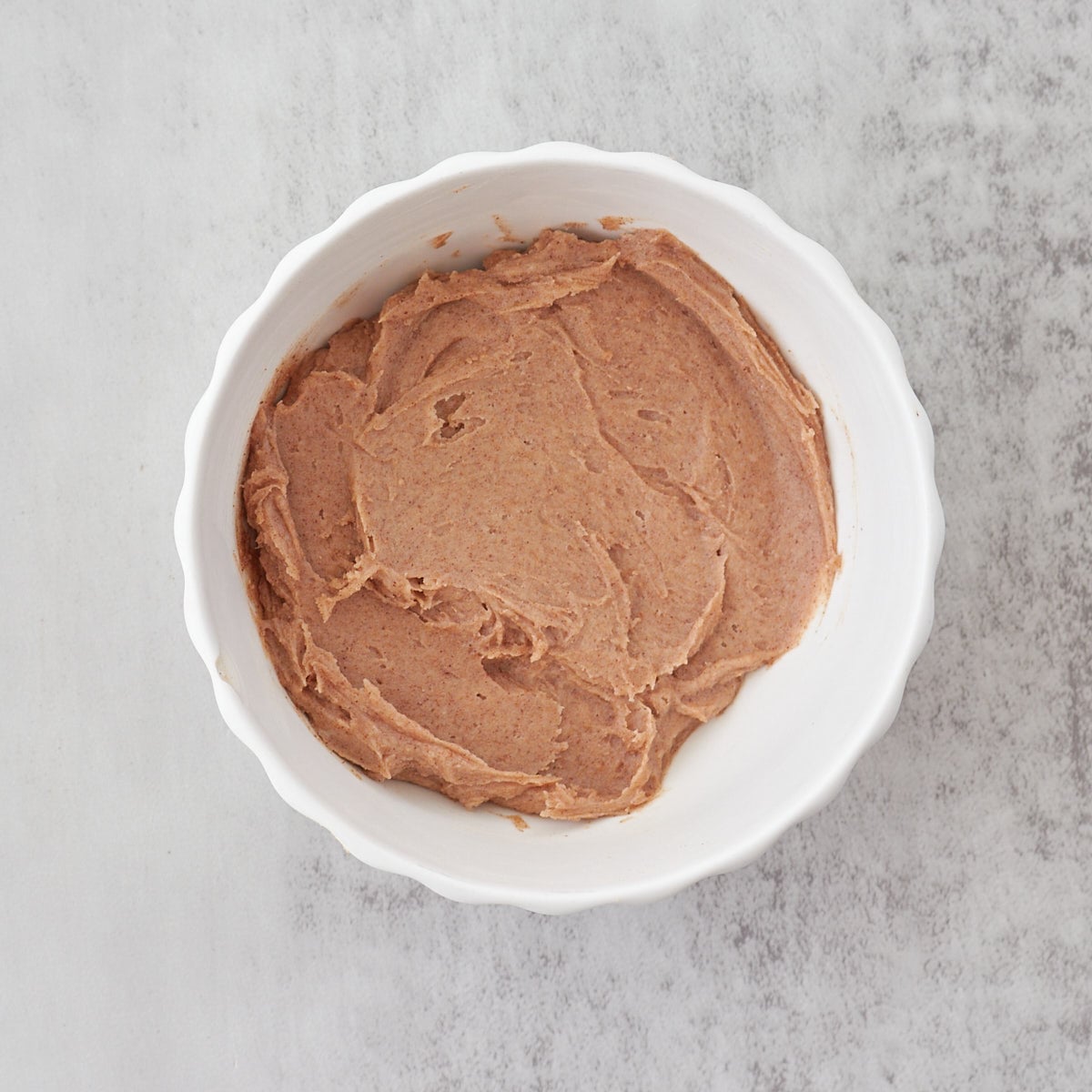 Cinnamon honey butter in a white bowl on a gray countertop.
