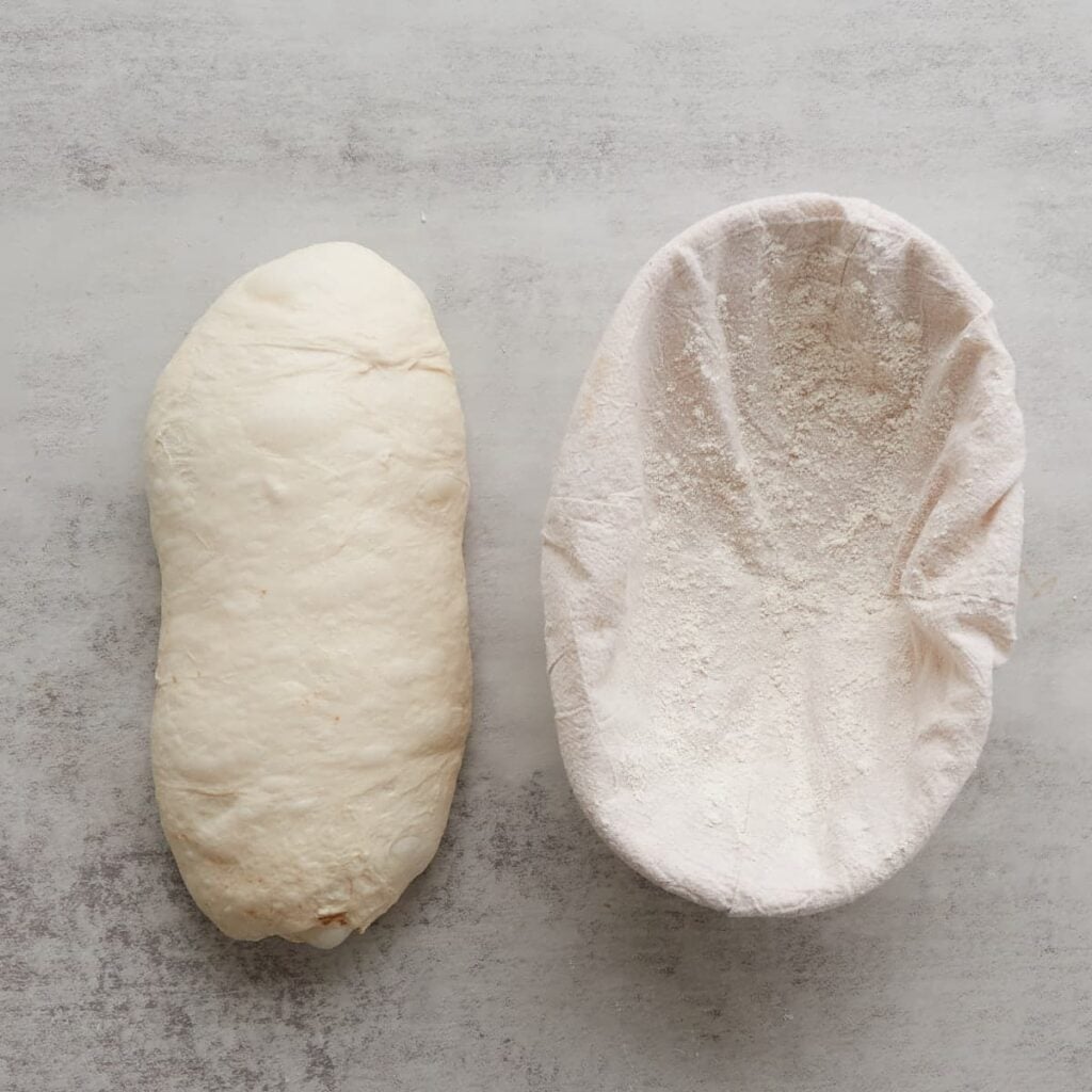 Shaped sourdough bread dough before adding to an oval lined proofing basket.