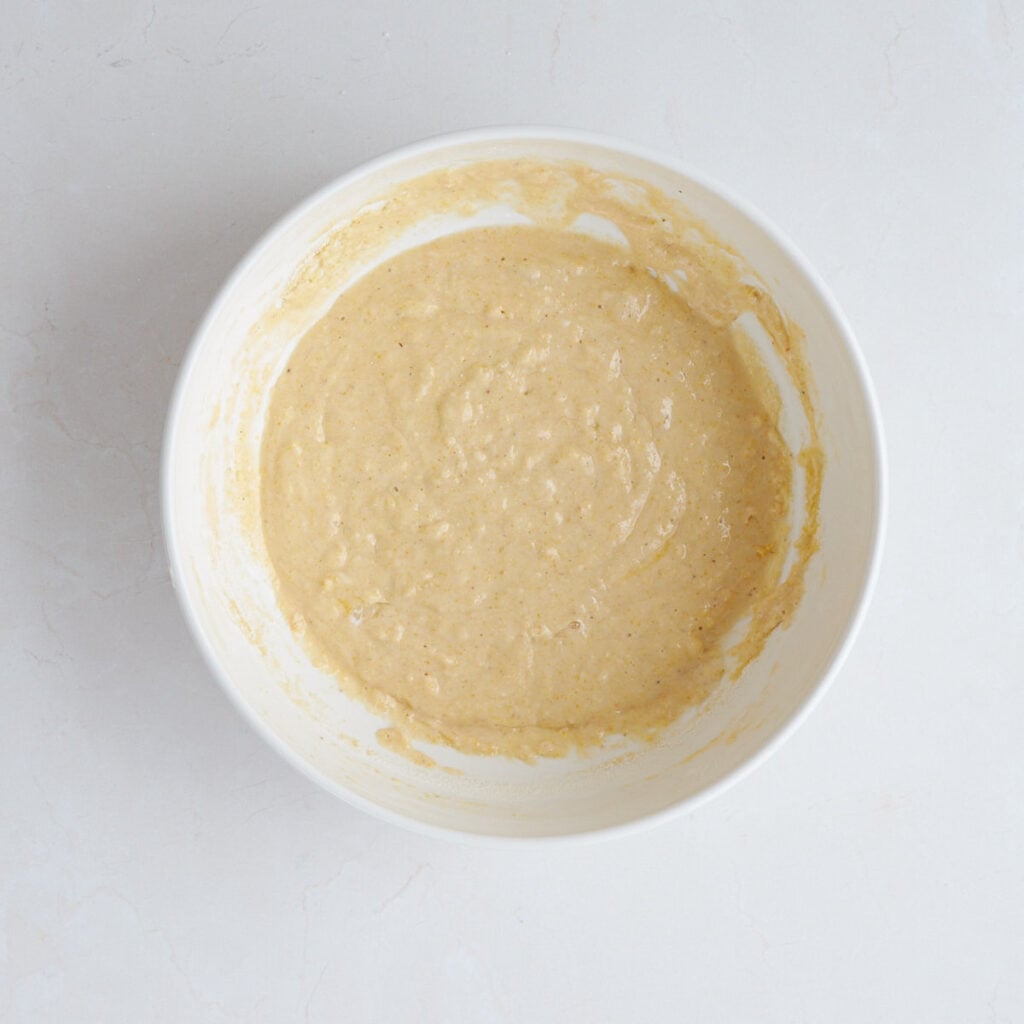 Corn bread batter mixed together in a white bowl.