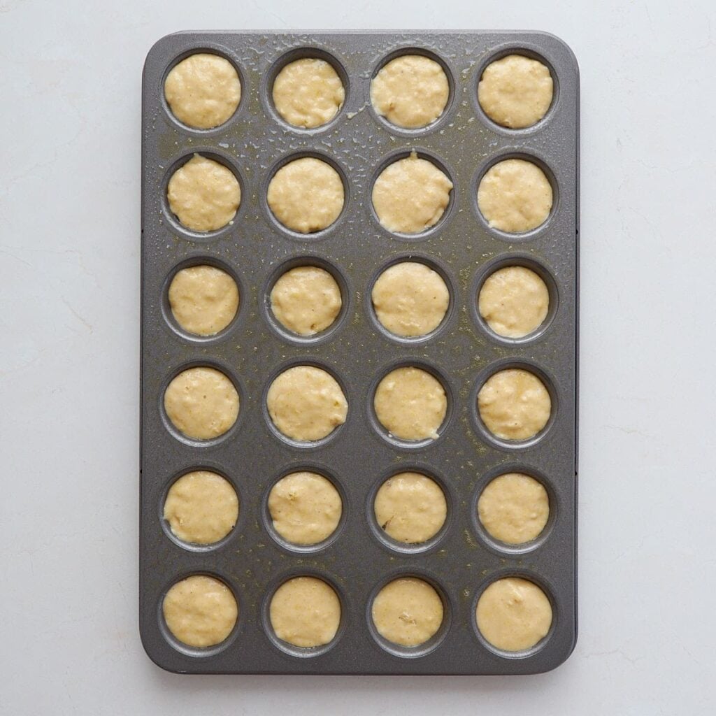Corn bread batter for sourdough mini corn dogs added to a greased mini muffin tin.