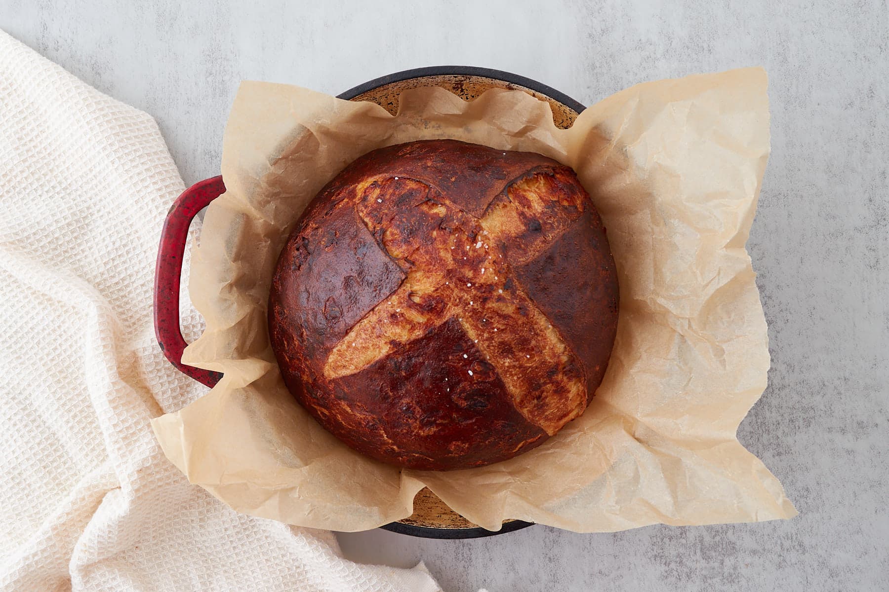 Top-down view of cheesy sourdough pretzel bread after baking resting on a sheet of parchment paper.