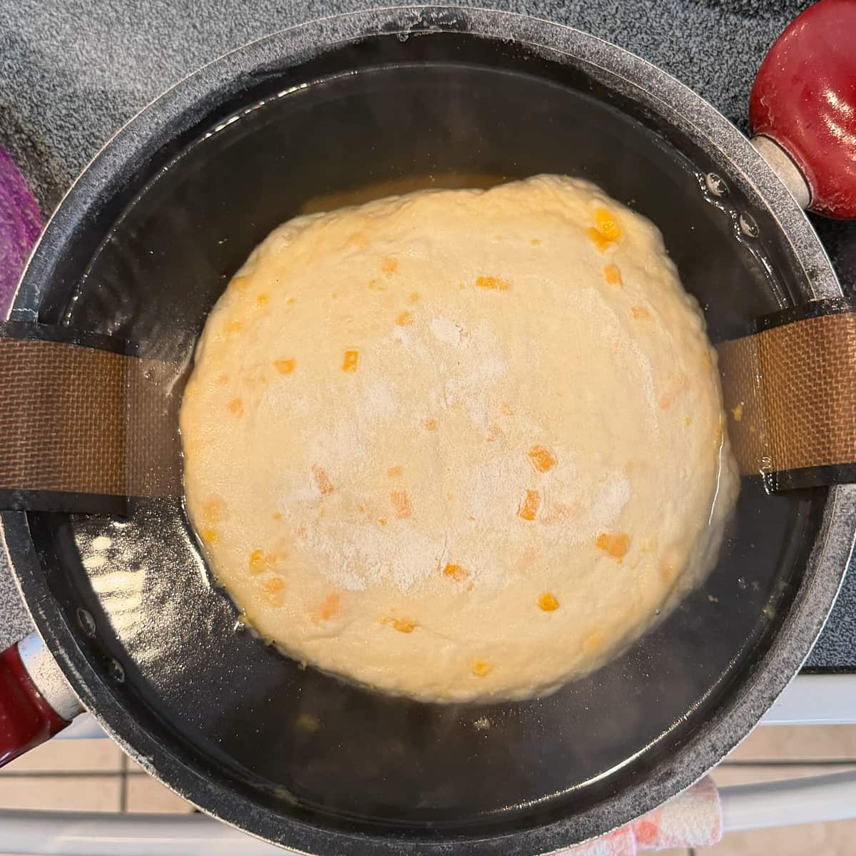 Cheesy sourdough pretzel bread dough boiling in a larger saucier.