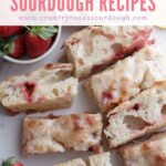 Strawberry lemon sourdough focaccia sliced on a white background with fresh strawberries.