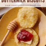 Sourdough Buttermilk Biscuit cut in half with honey, butter and jelly on a yellow plate.