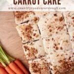 Sourdough Carrot Cake with cream cheese frosting cut into slices next to fresh carrots.